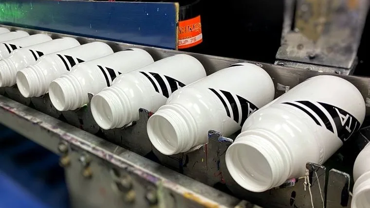 Des bidons sur le carrousel de sérigraphie de l’atelier de Sissonne